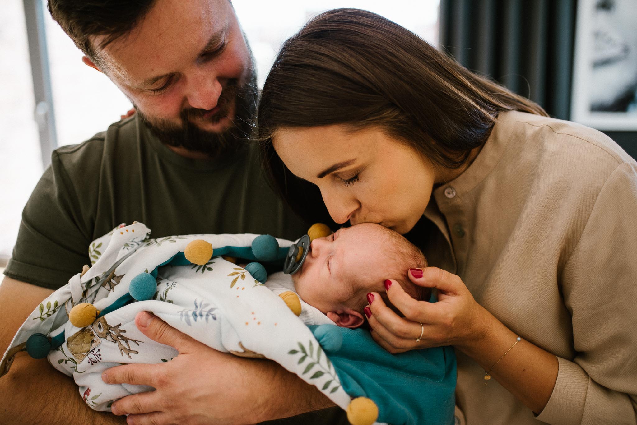 Mama całuje noworodka w czoło - sesja noworodkowa lifestyle w Poznaniu