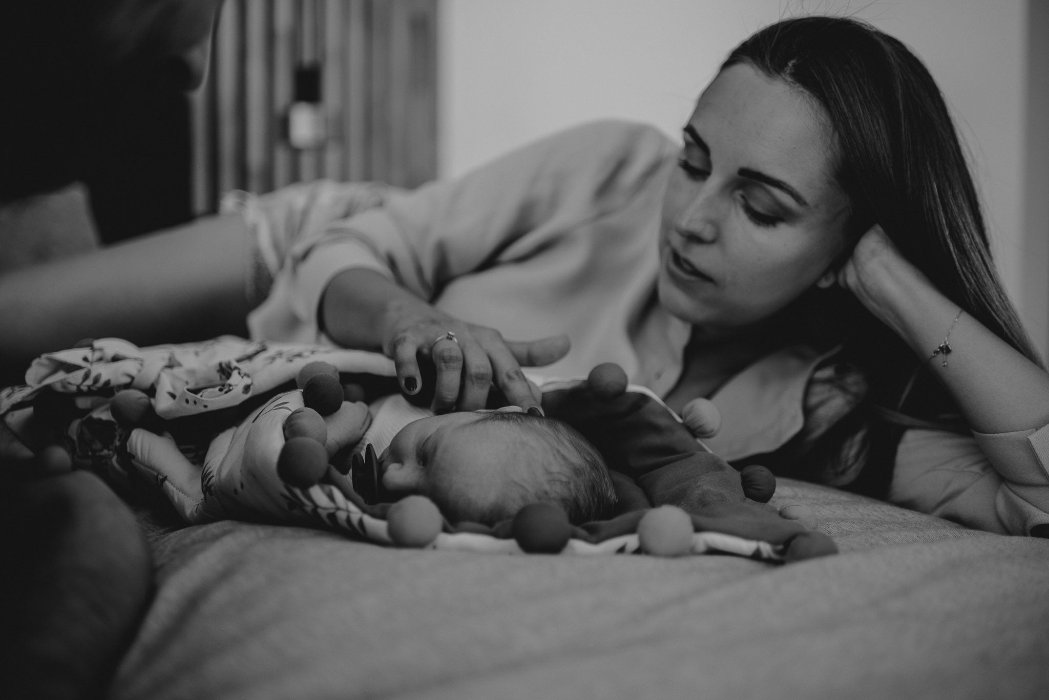 Mama głaszcze niemowlaka po twarzy - sesja noworodkowa lifestyle w Poznaniu