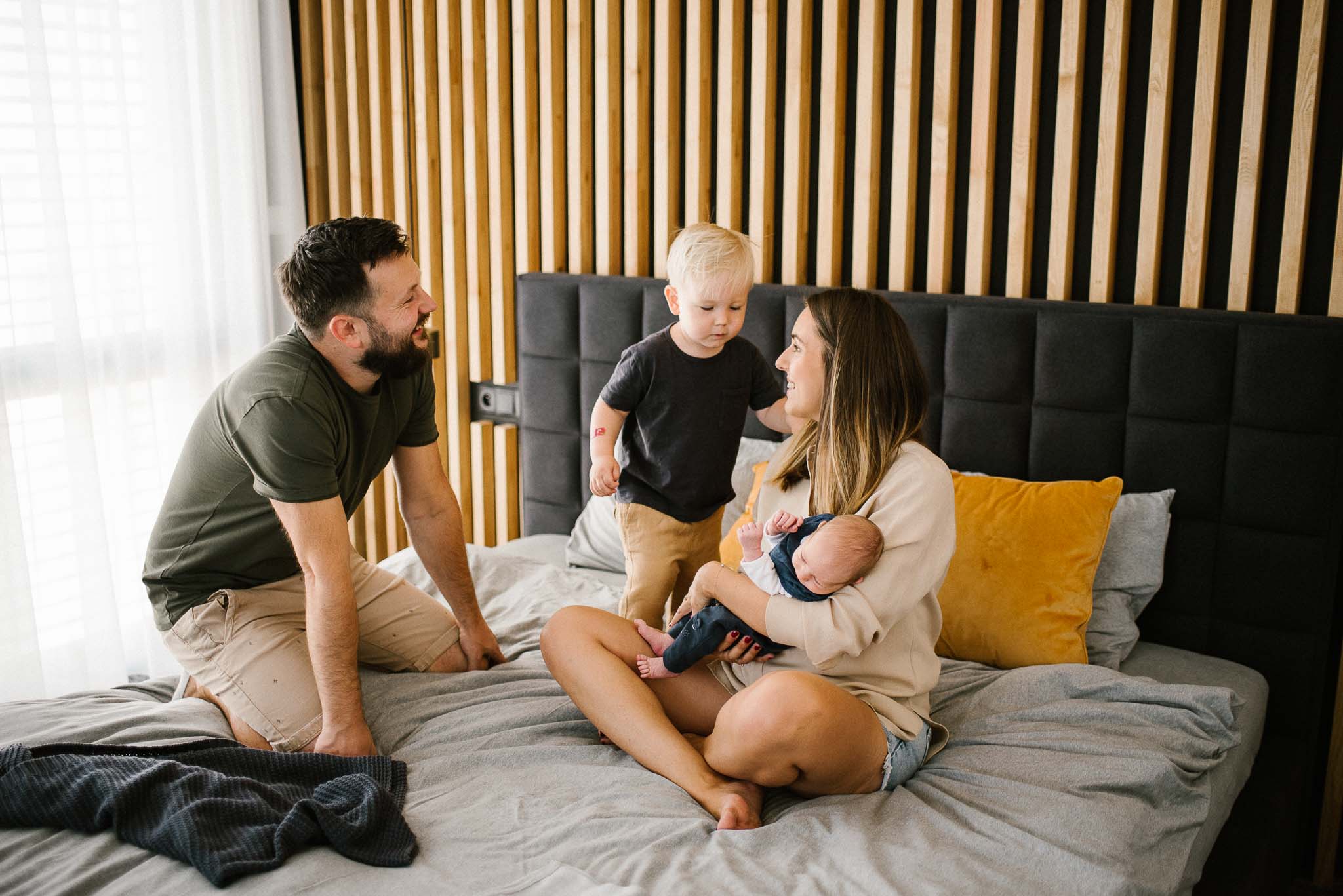 Rodzina z noworodkiem bawią się na łóżku -sesja noworodkowa lifestyle w Poznaniu