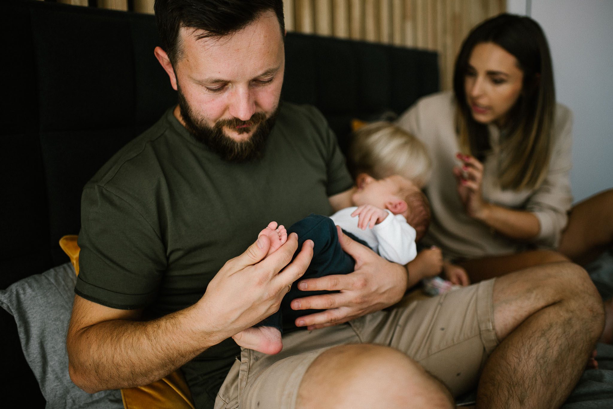 tata trzyma noworodka na rękach - sesja noworodkowa lifestyle w Poznaniu
