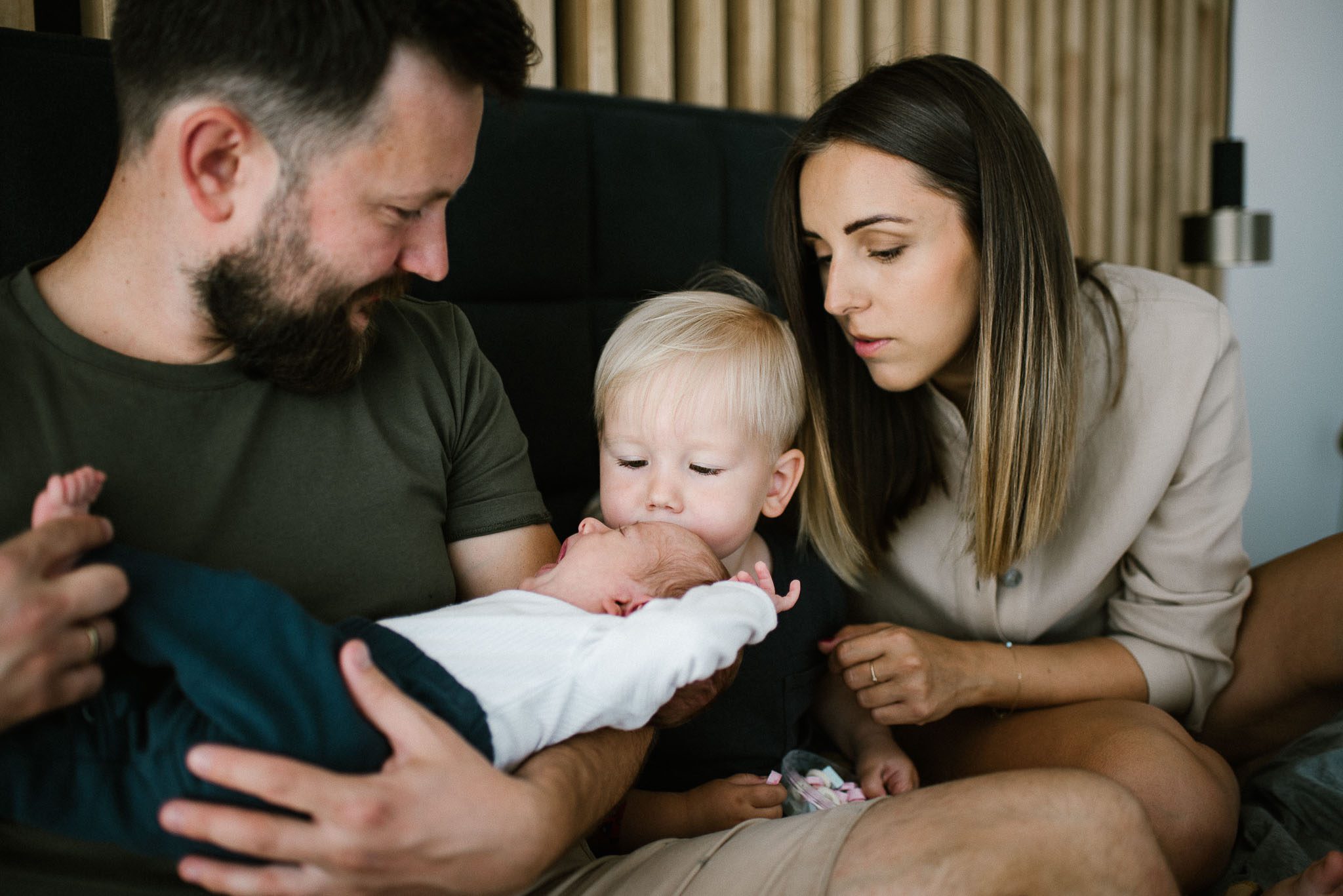 Rodzina na łóżku z noworodkiem - sesja noworodkowa lifestyle w Poznaniu