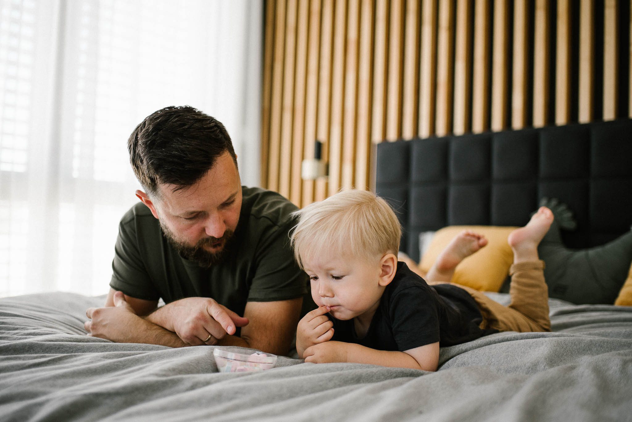 Tata z chłopcem leżą na łóżku - sesja noworodkowa lifestyle w Poznaniu