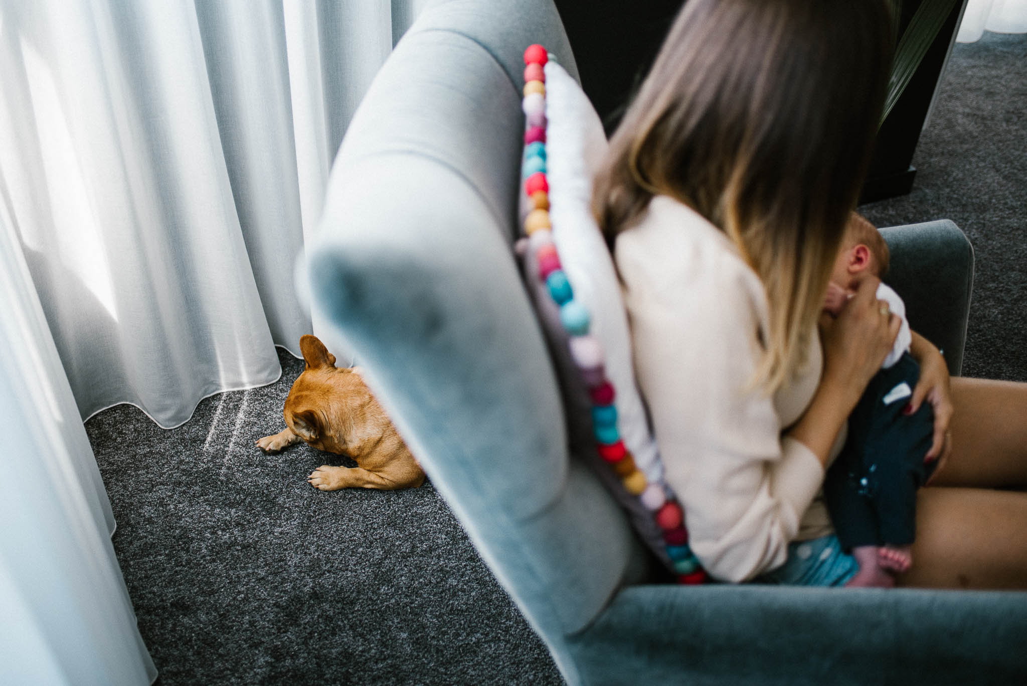 mam karmi noworodka piersią na fotelu - sesja noworodkowa lifestyle w Poznaniu