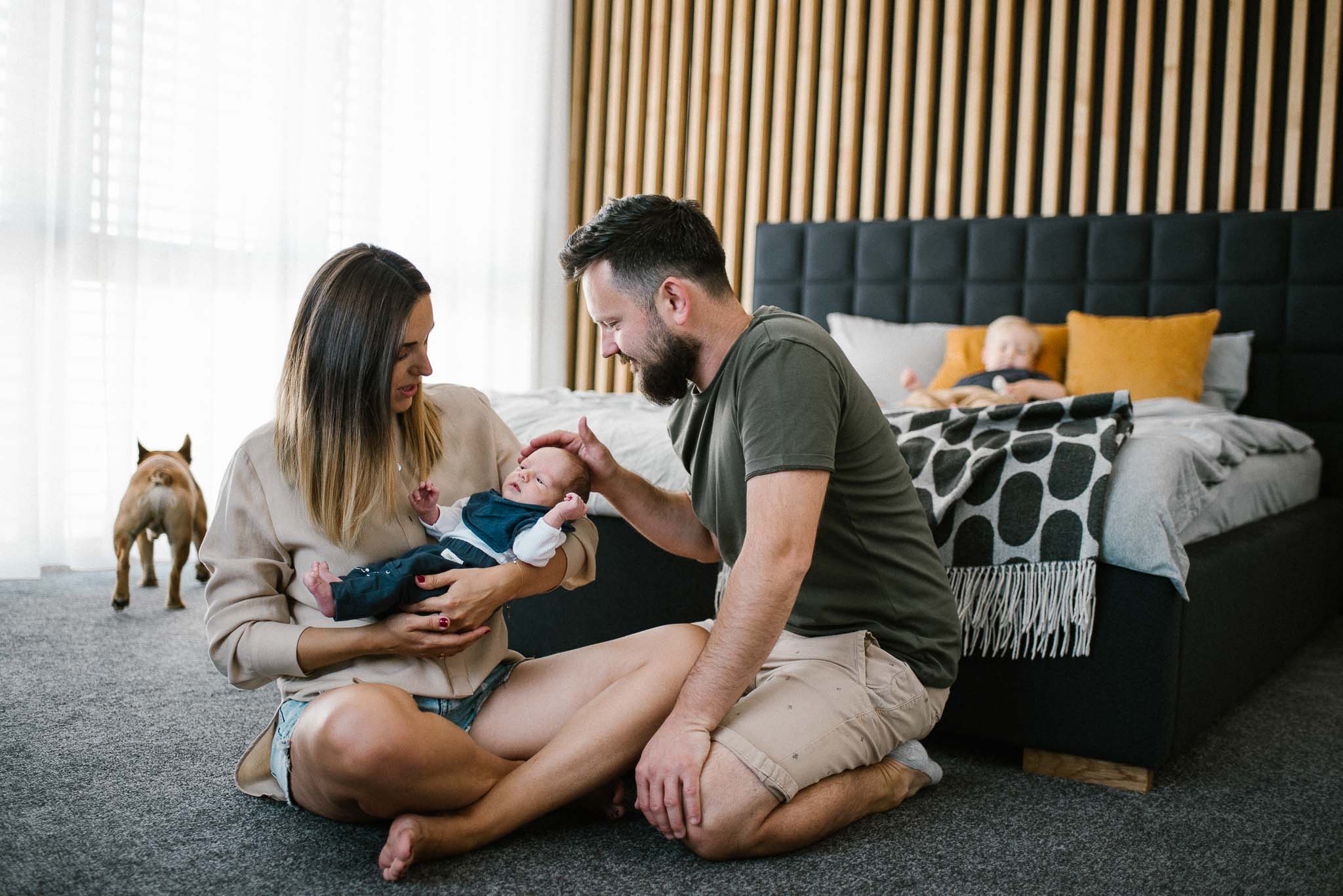 Rodzice siedzą z noworodkiem na podłodze - sesja noworodkowa lifestyle w Poznaniu