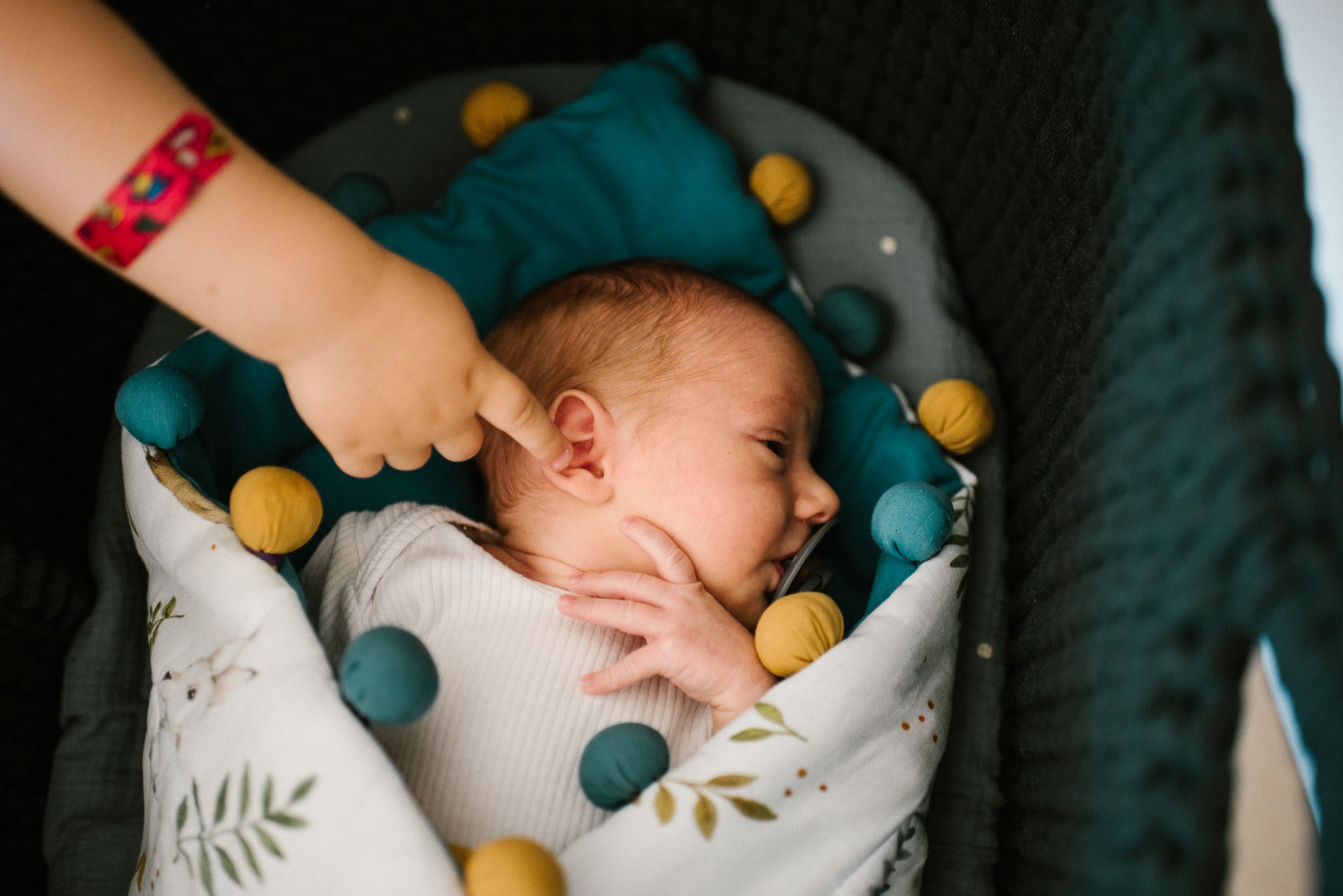 Chłopiec dotyka palcem noworodka - sesja noworodkowa lifestyle w Poznaniu