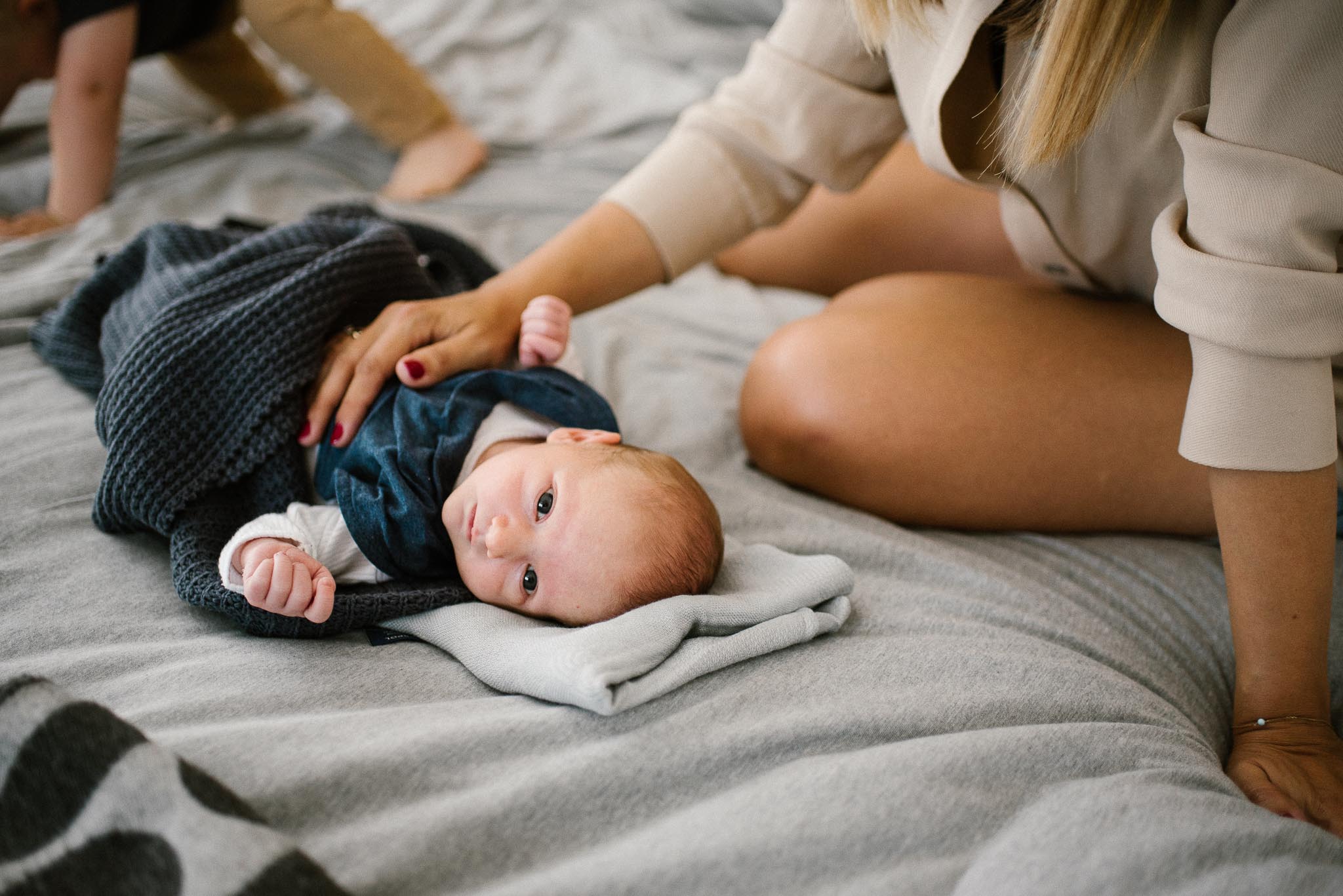 Noworodek leży na łóżku - sesja noworodkowa lifestyle w Poznaniu