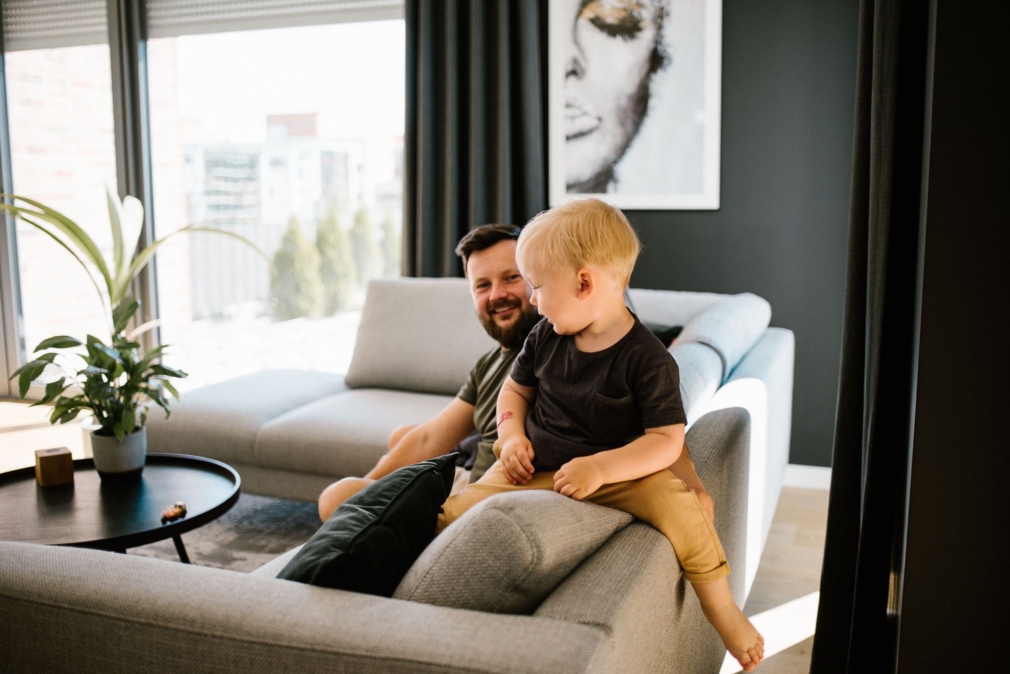 Chłopiec bawi się z tatą na kanapie - sesja noworodkowa lifestyle w Poznaniu