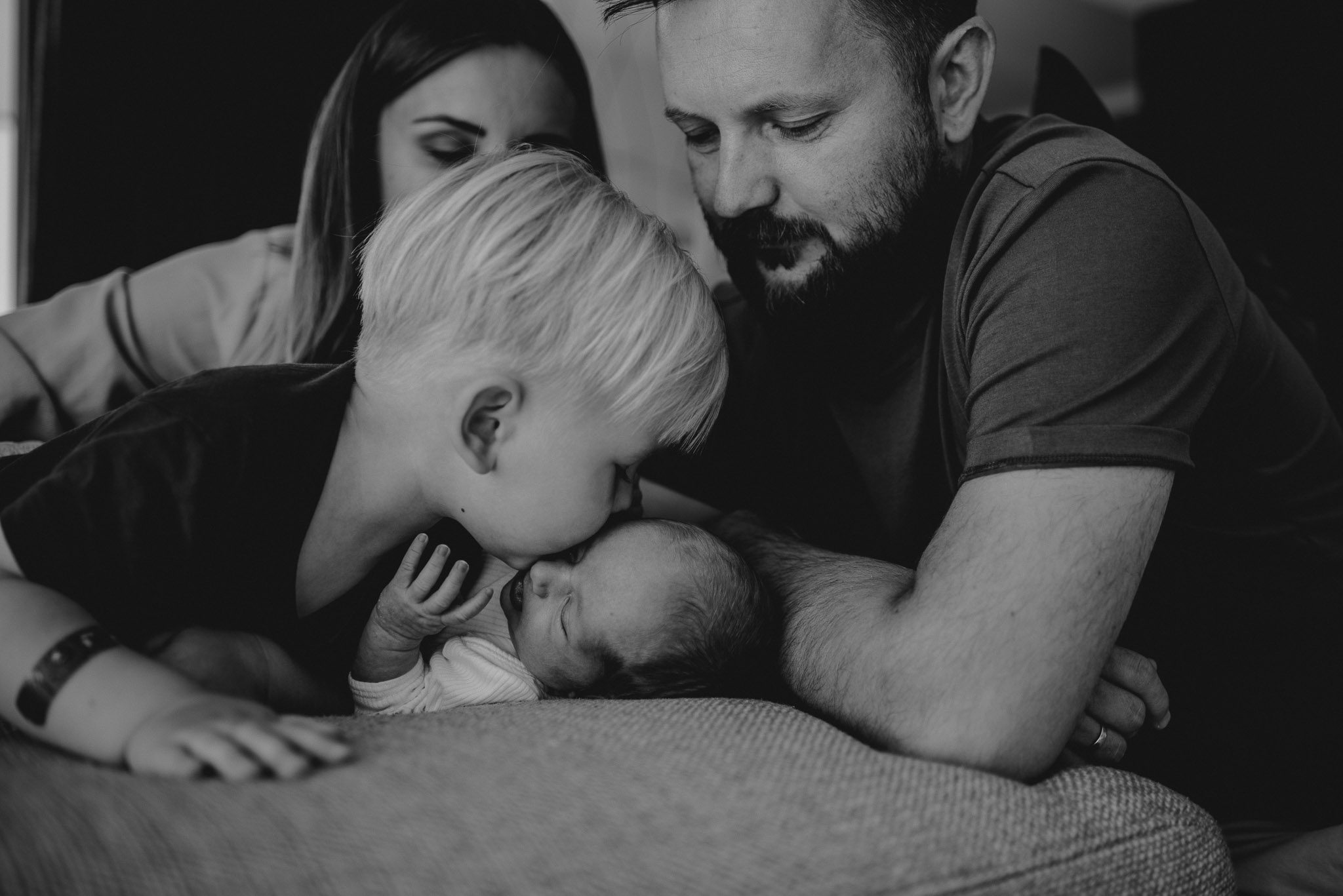 Chłopiec daje buziaka noworodkowi - sesja noworodkowa lifestyle w Poznaniu