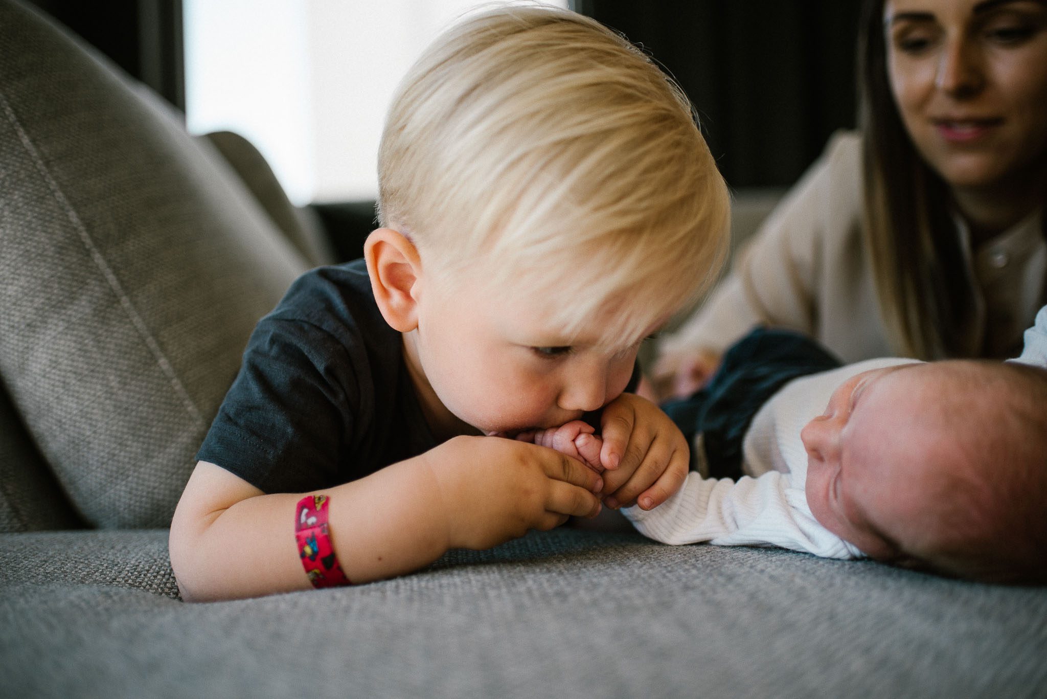 Chłopiec całuje rączkę noworodka - sesja noworodkowa lifestyle w Poznaniu