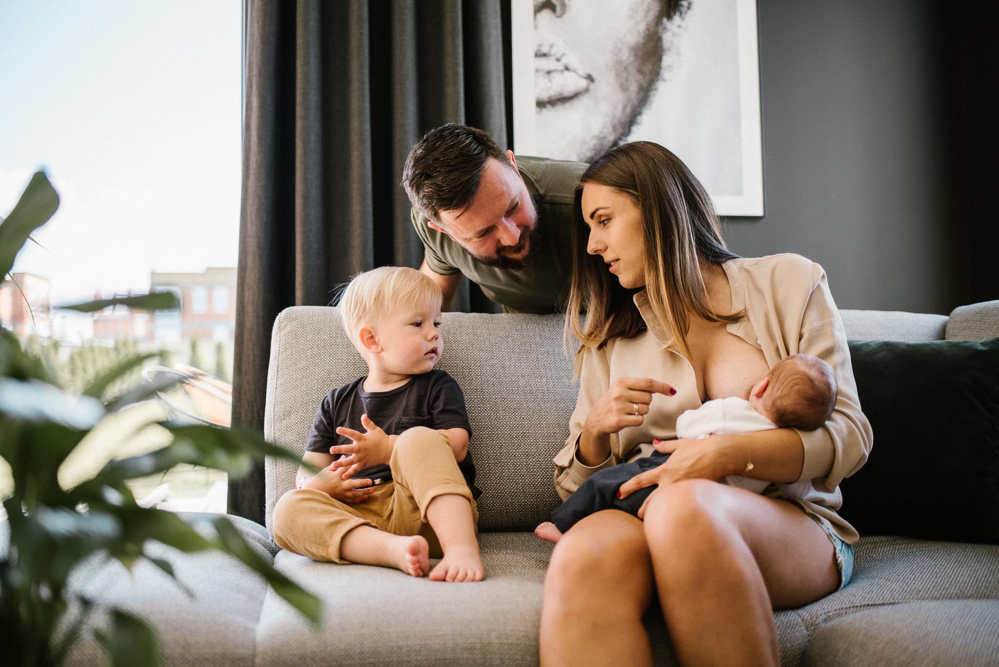 Rodzina na kanapie, mama karmi piersią noworodka - sesja noworodkowa lifestyle w Poznaniu