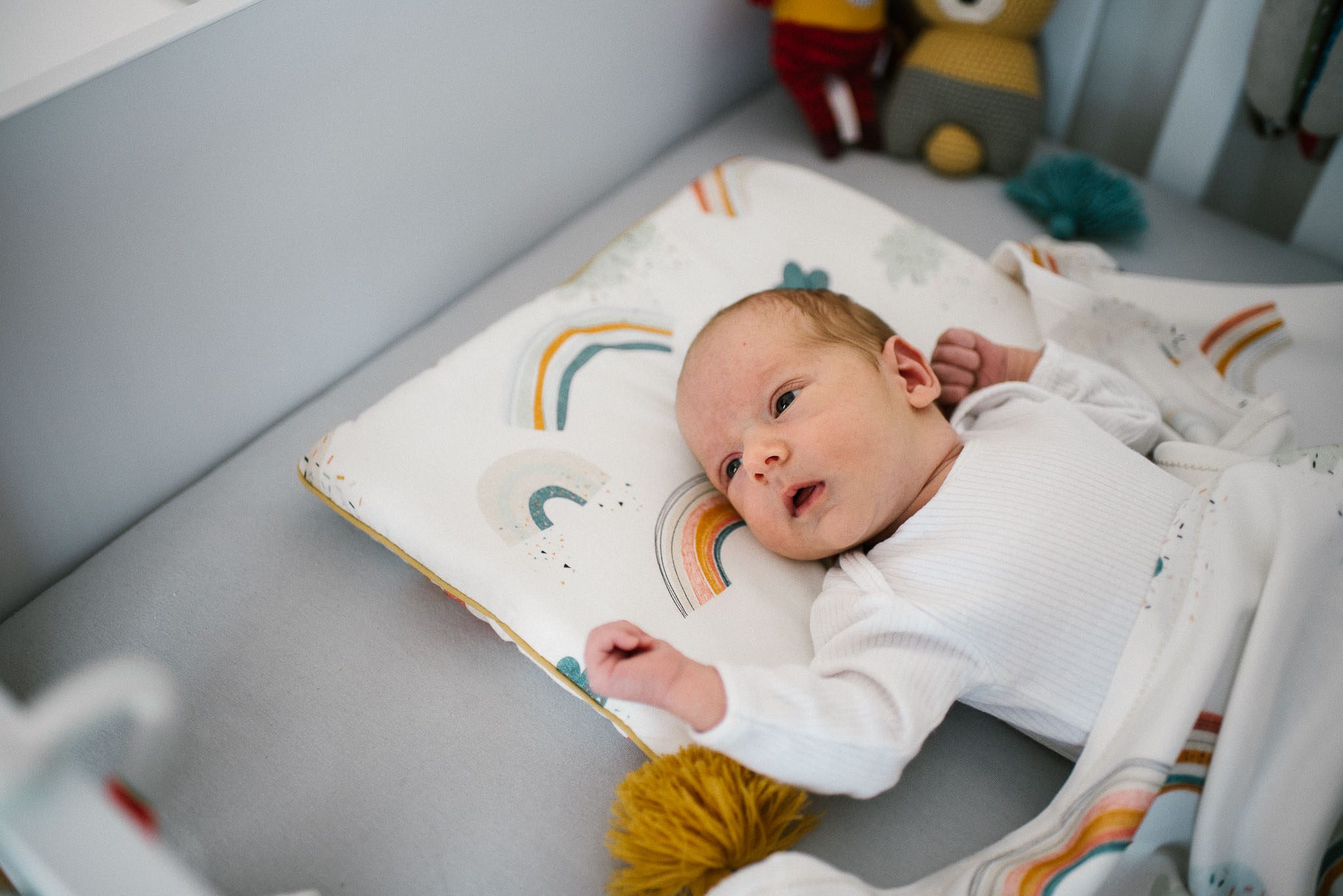 Noworodek leży w łóżeczku - sesja noworodkowa lifestyle w Poznaniu