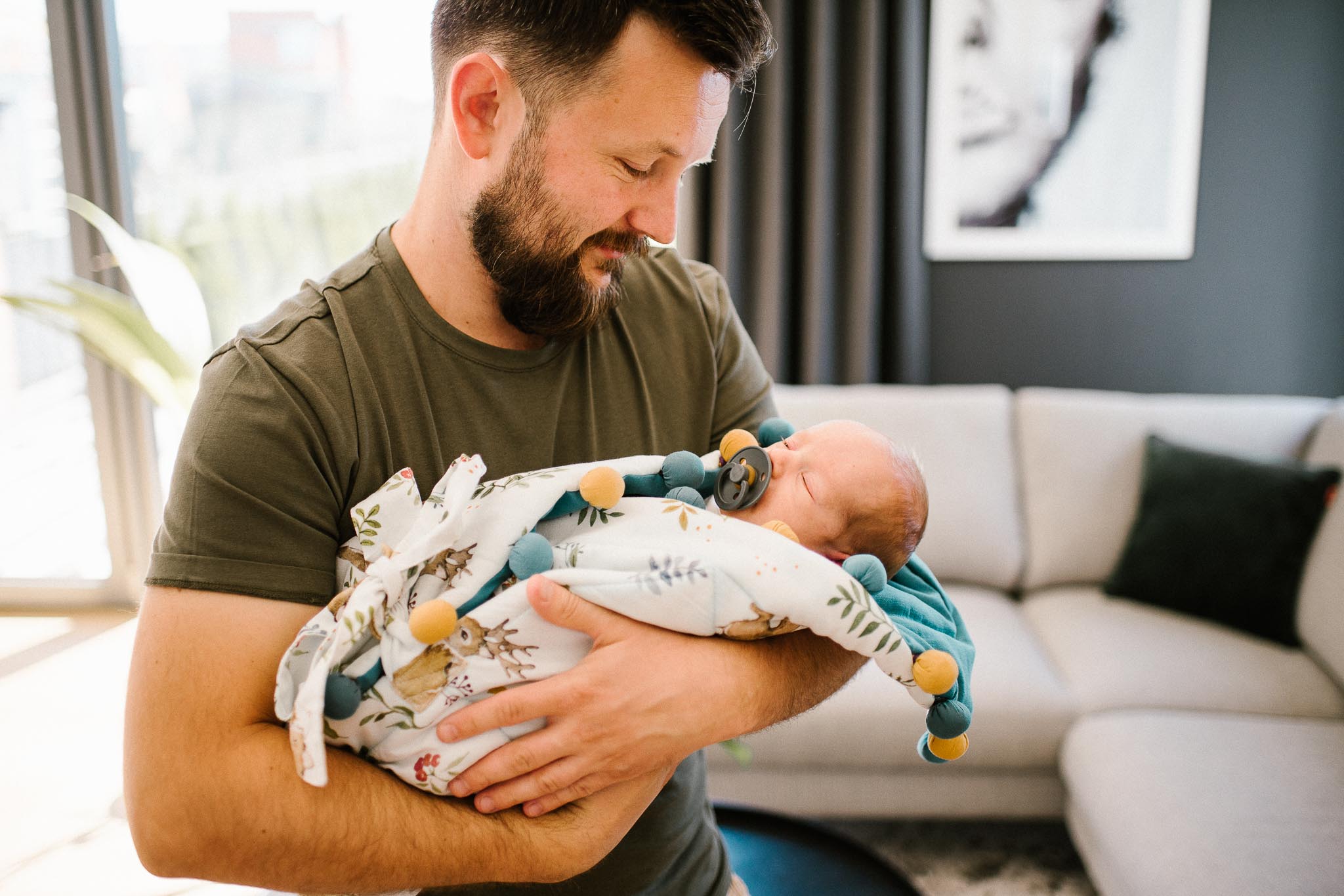 tata trzyma noworodka w rożku na rękach - sesja noworodkowa lifestyle w Poznaniu