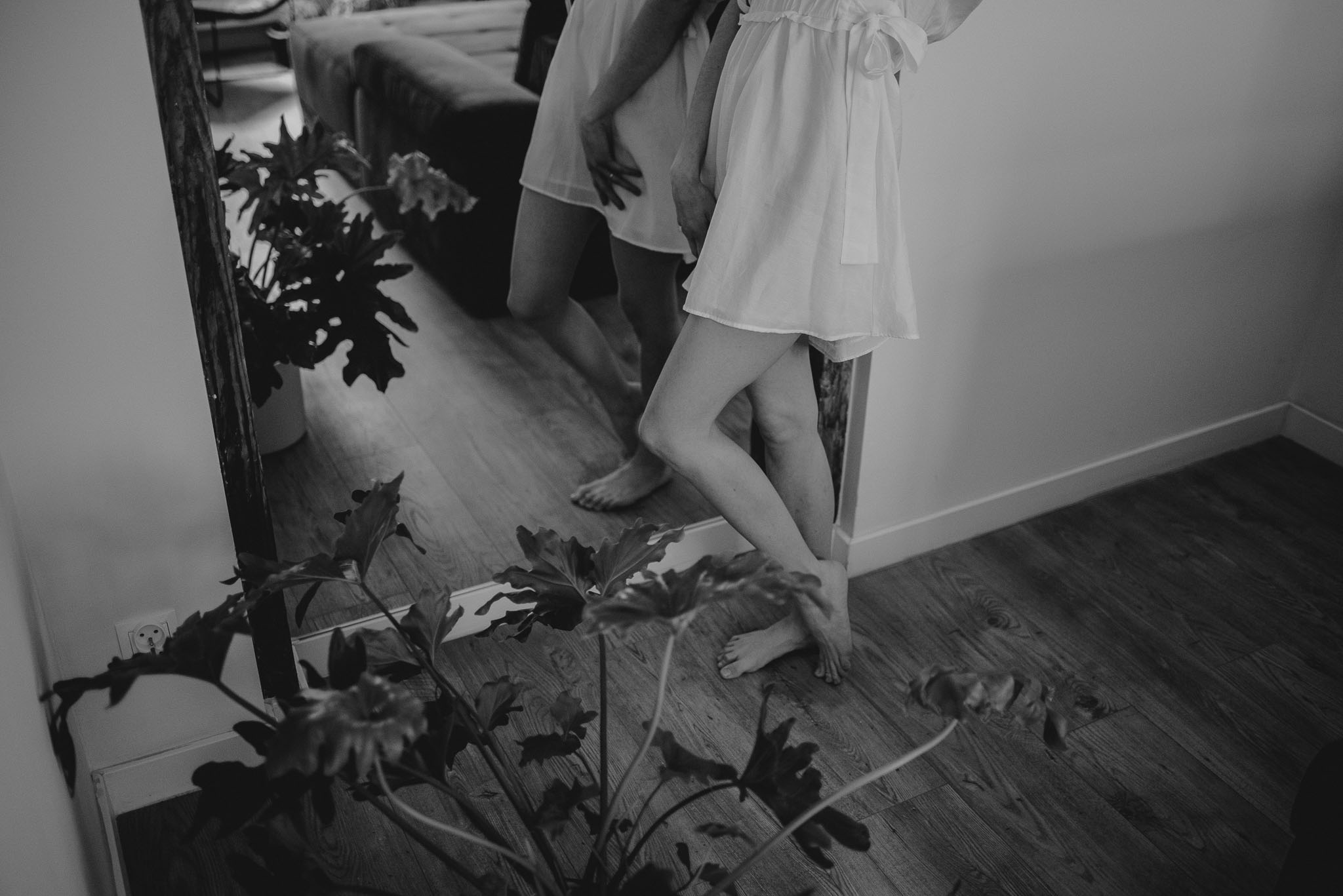 Kobieta stoi przed&nbsp;lustrem podczas sesji kobiecej i&nbsp;się przygląda, zbliżenie na&nbsp;nogi