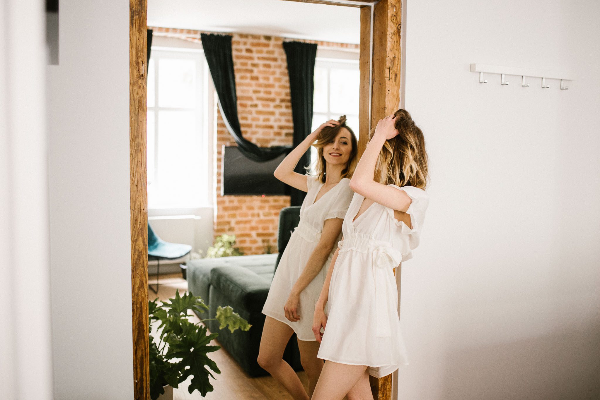 Kobieta podczas sesji kobiecej przegląda się w&nbsp;lustrze w&nbsp;apartamencie