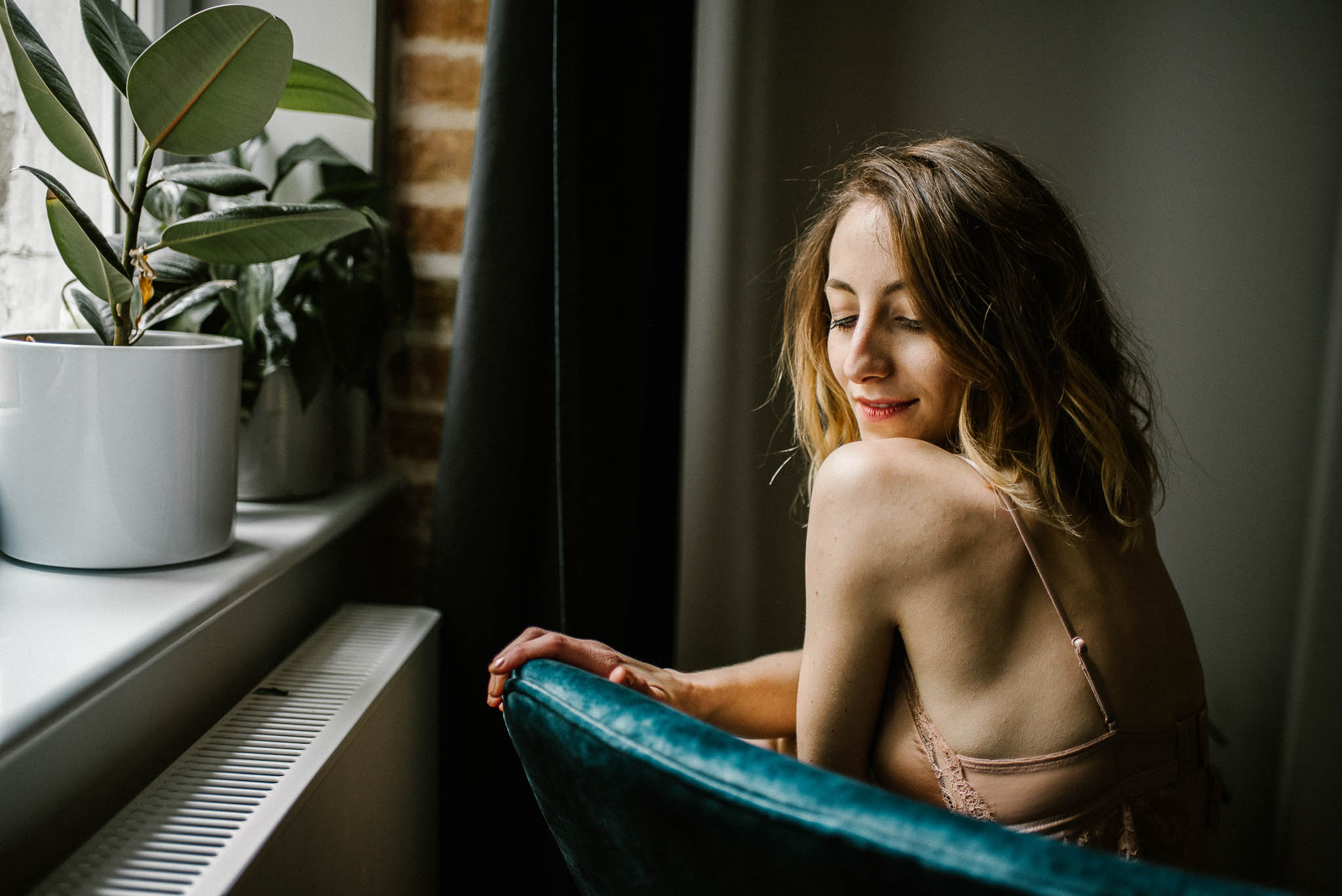 Kobieta siedzi na&nbsp;fotelu - sesja kobieca w&nbsp;apartamencie w&nbsp;Poznaniu