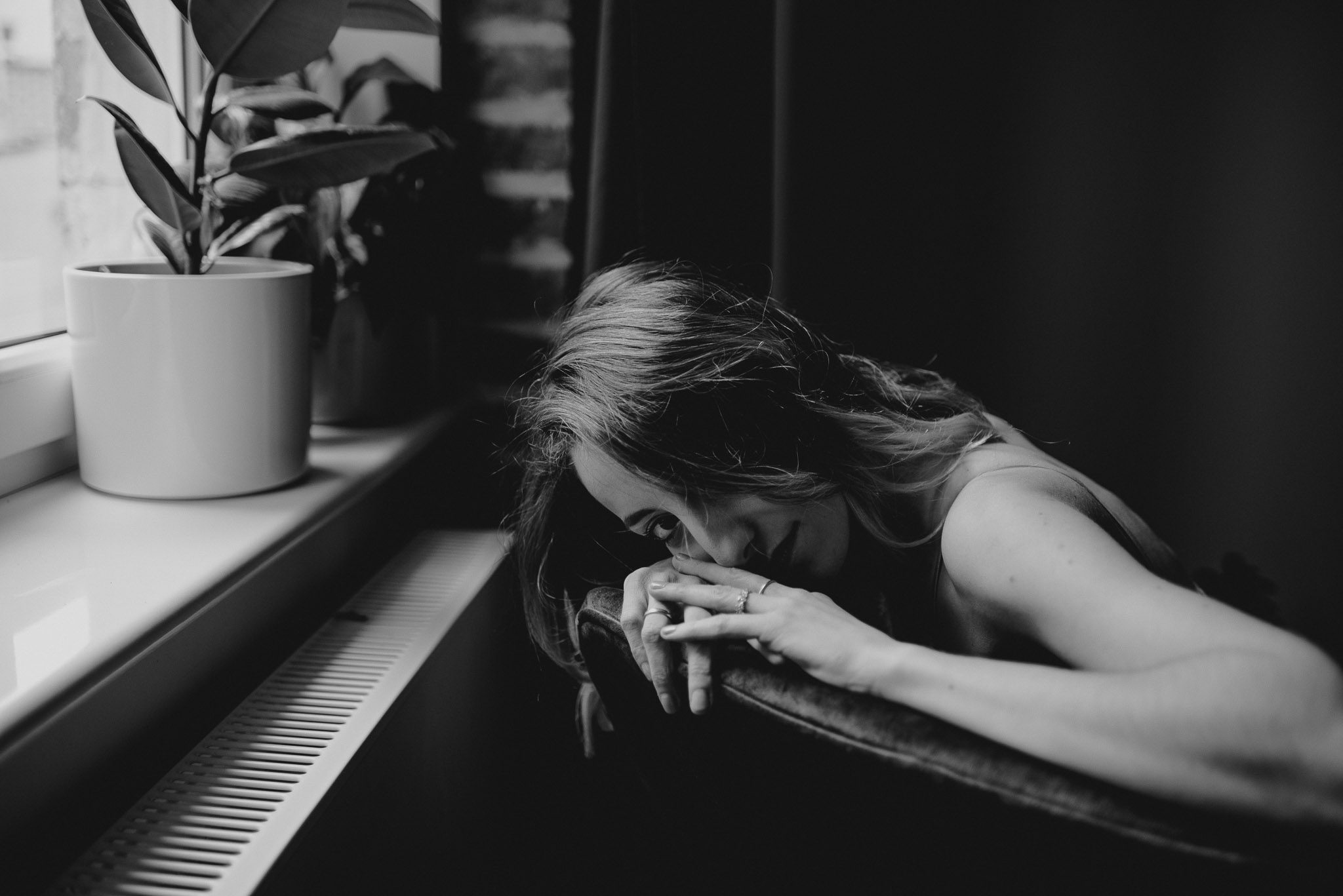 Kobieta siedzi na&nbsp;fotelu i&nbsp;opiera się rękami o&nbsp;oparcie - sesja kobieca w&nbsp;apartamencie w&nbsp;Poznaniu