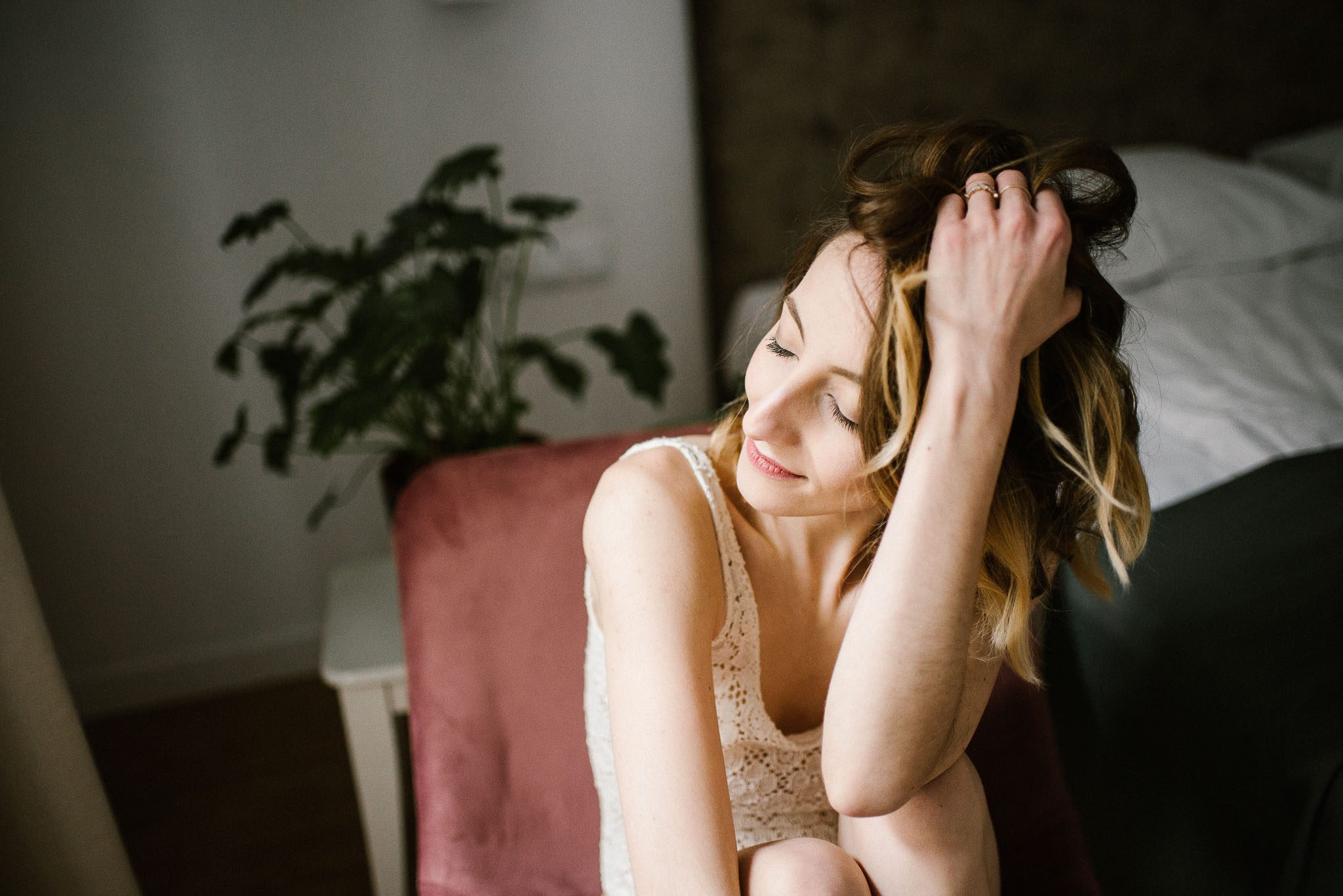 Kobieta w&nbsp;bieliźnie na&nbsp;fotelu bawi się włosami - sesja kobieca w&nbsp;apartamencie w&nbsp;Poznaniu
