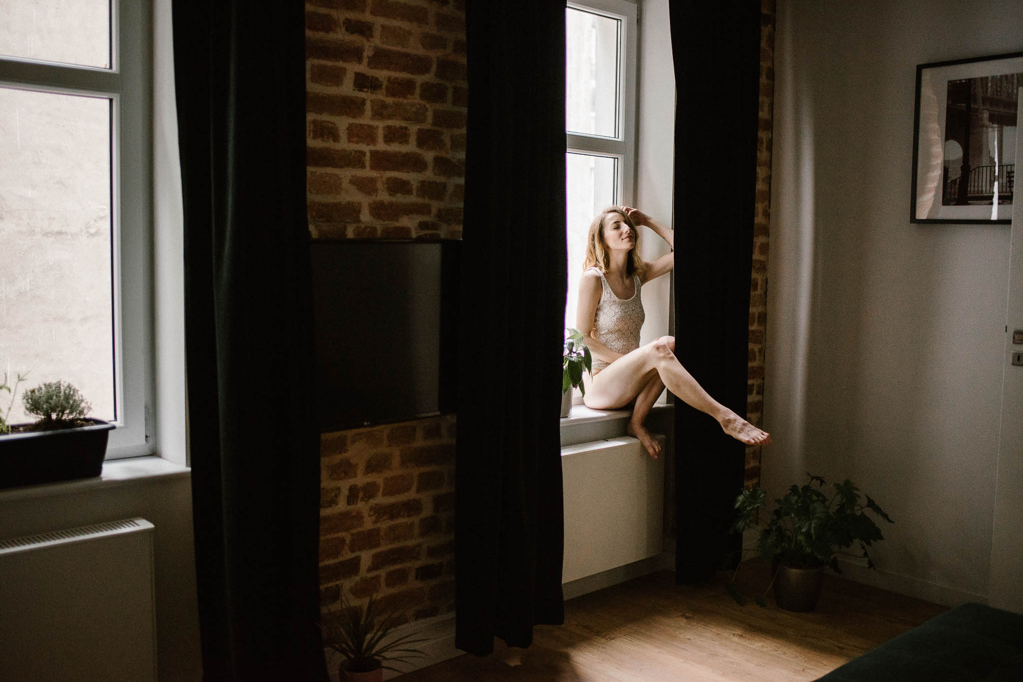 Kobieta w&nbsp;bieliźnie siedzi na&nbsp;parapecie - sesja kobieca w&nbsp;apartamencie w&nbsp;Poznaniu