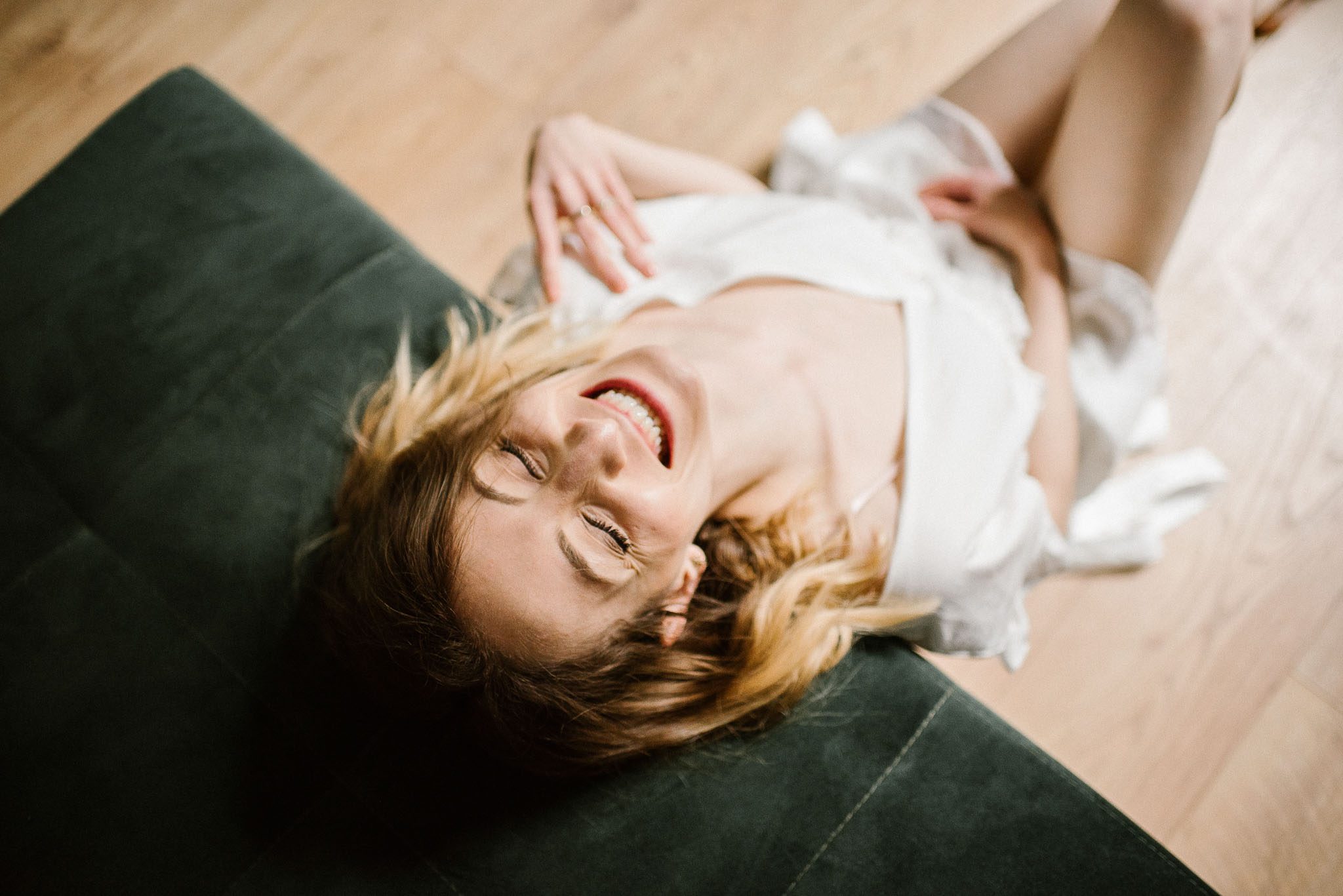 Kobieta uśmiecha się i&nbsp;opiera się o&nbsp;sofę podczas sesji kobiecej