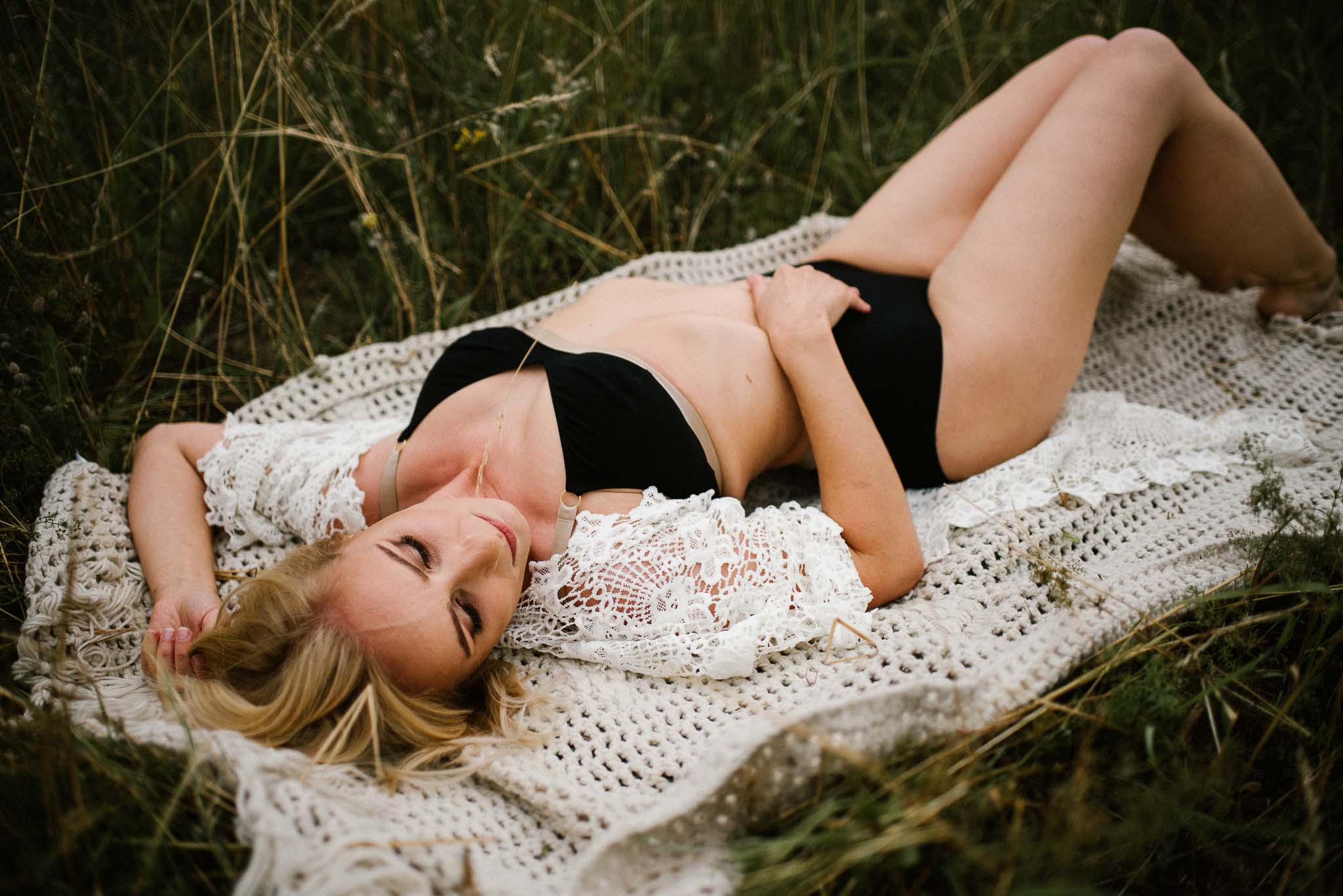 Kobieta leży na&nbsp;kocu na&nbsp;łące w&nbsp;bieliźnie - sesja kobieca sensualna w&nbsp;plenerze Poznań