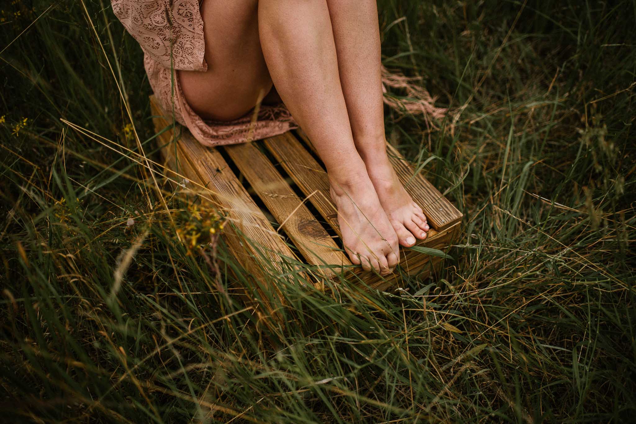 Kobieta siedzi na&nbsp;drewnianej skrzyni - sesja kobieca sensualna w&nbsp;plenerze Poznań