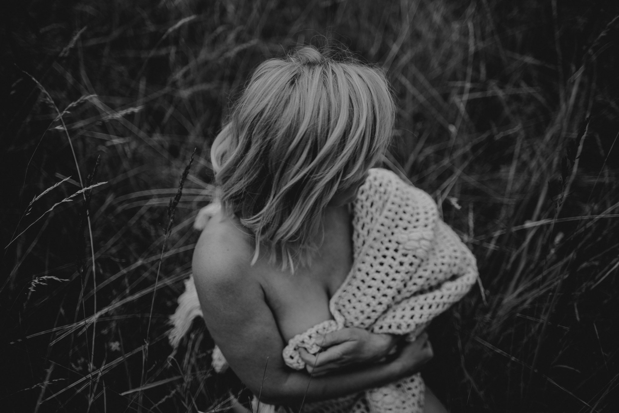 Kobieta zasłania piersi siedząc na&nbsp;łące - sesja kobieca sensualna w&nbsp;plenerze Poznań