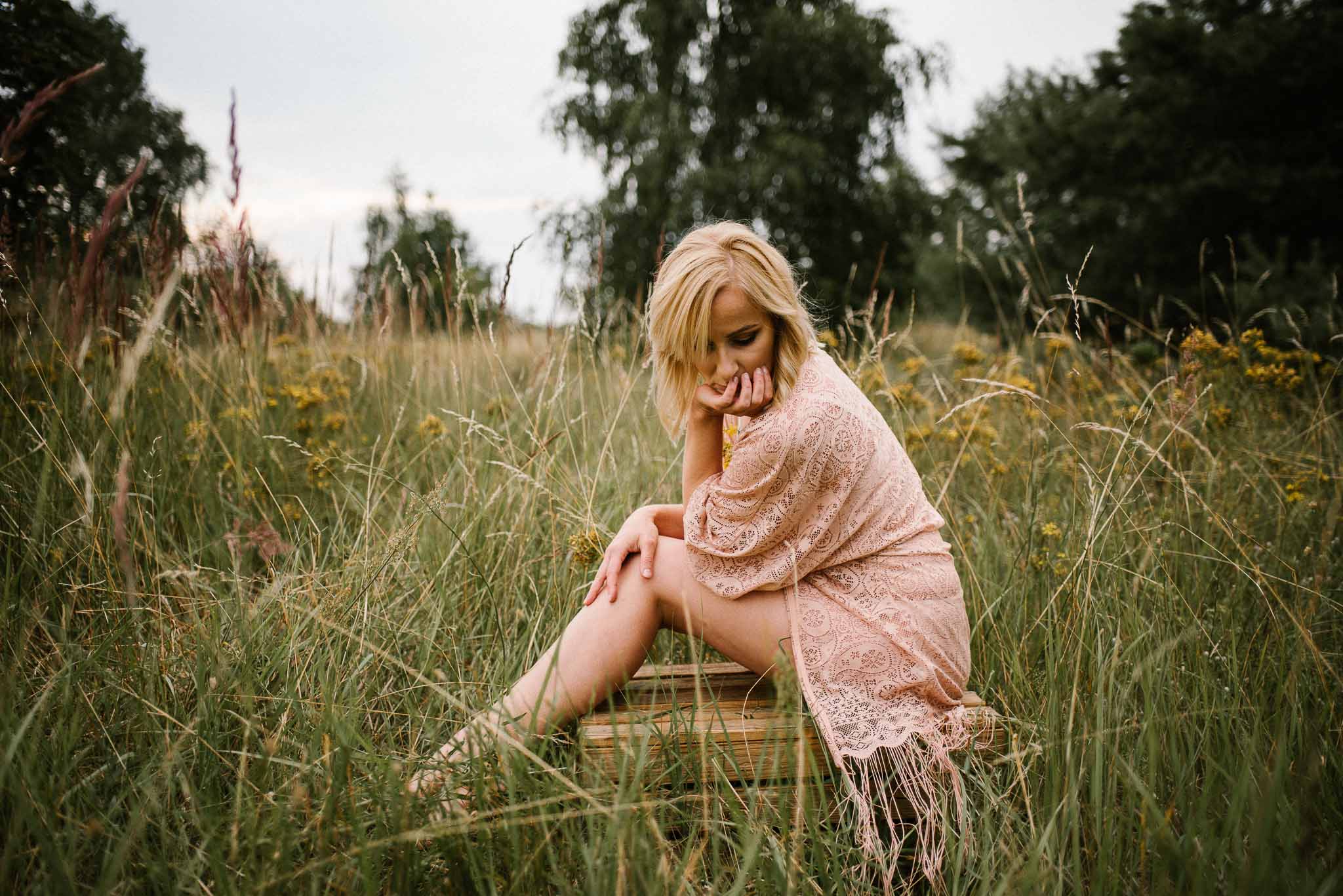 Kobieta siedzi na&nbsp;skrzyni na&nbsp;łące - sesja kobieca sensualna w&nbsp;plenerze Poznań
