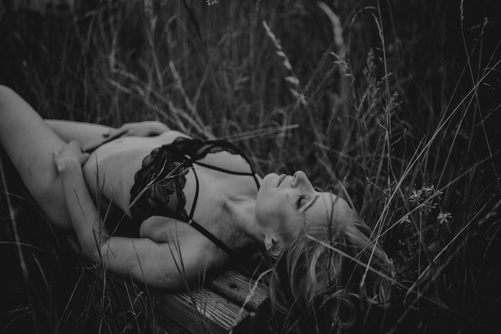 Kobieta leży na&nbsp;łące w&nbsp;bieliźnie - sesja kobieca sensualna w&nbsp;plenerze Poznań