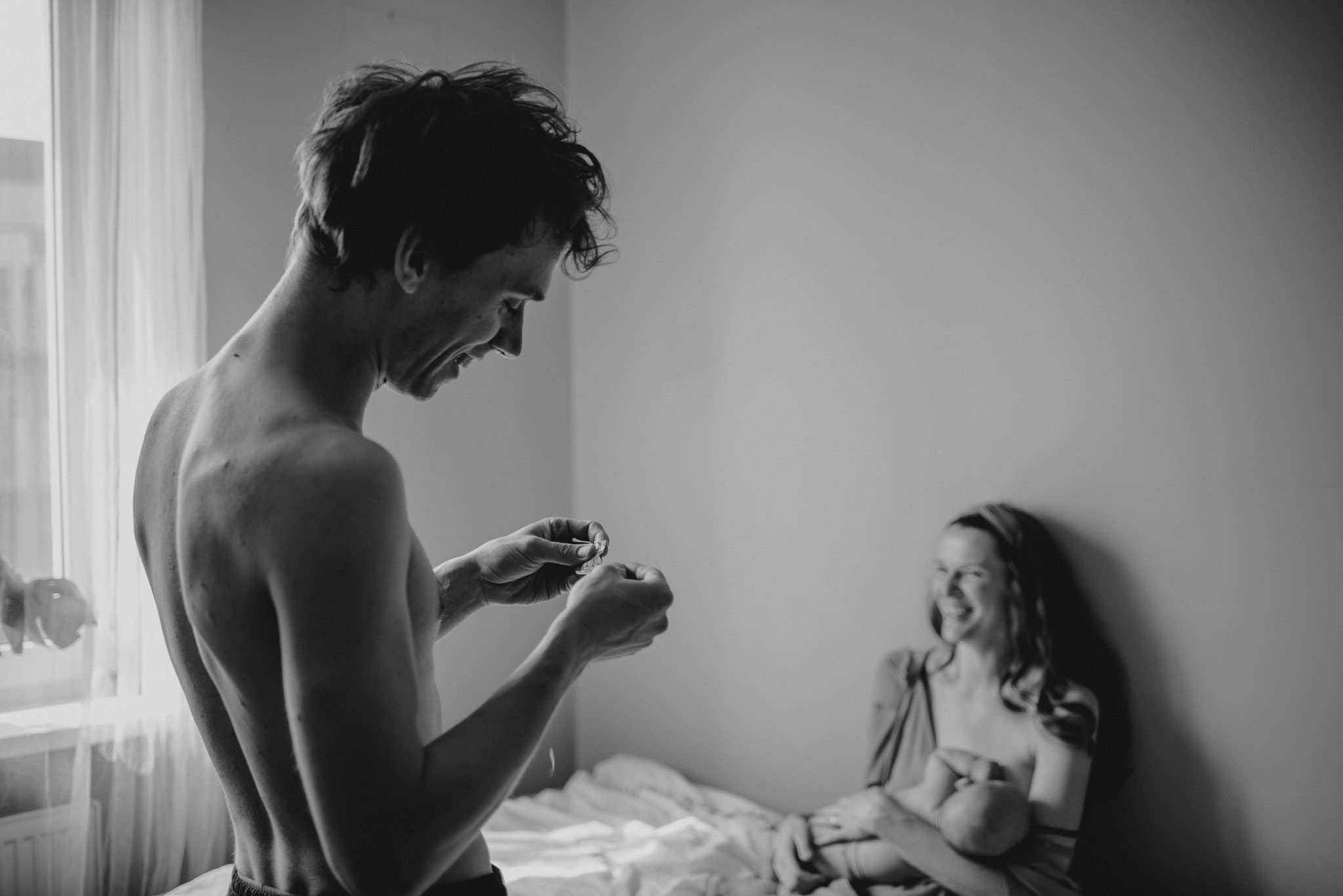 Mąż nakleja żonie plaster na&nbsp;nogę - sesja niemowlęca lifestyle w&nbsp;domu Poznań