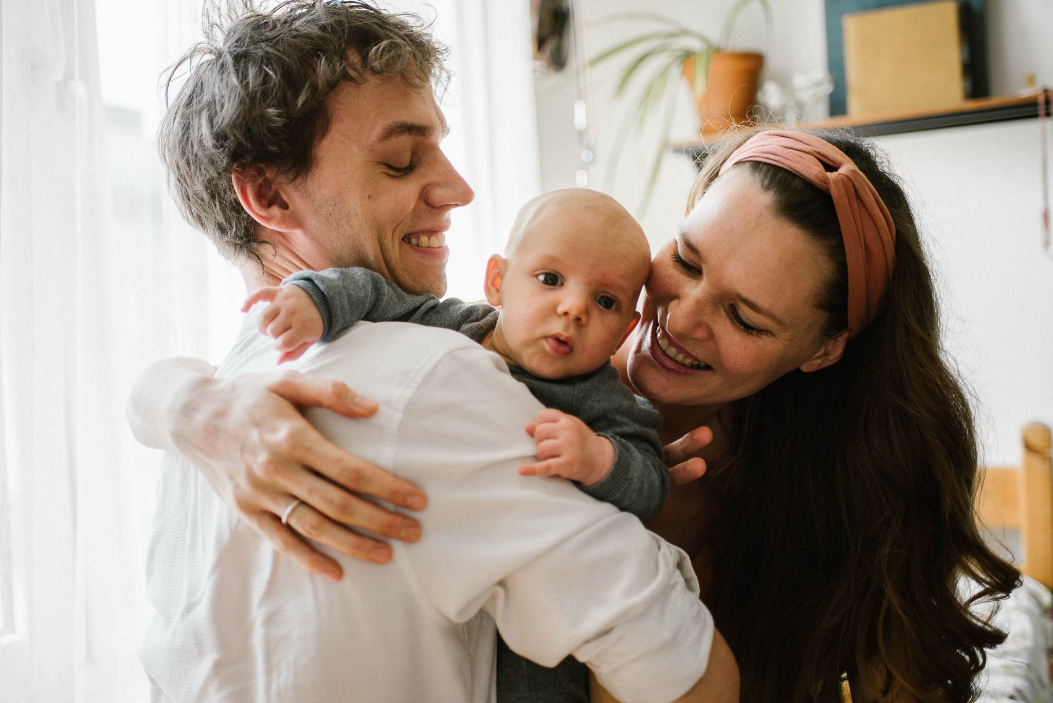 Rodzice przytulają niemowlę -Sesja niemowlęca lifestyle w&nbsp;domu Poznań