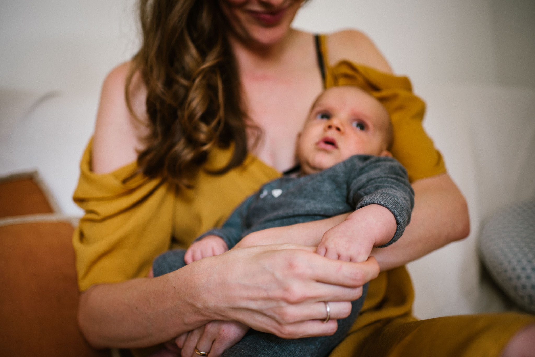 Mama siedzi z&nbsp;niemowlęciem na&nbsp;sofie - Sesja niemowlęca lifestyle w&nbsp;domu Poznań